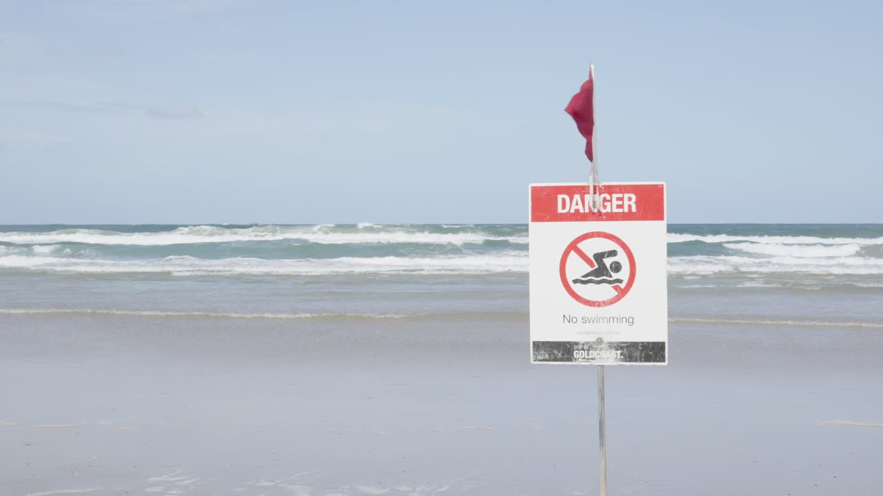 Close up Danger Sign and red flag on empty australian beach.