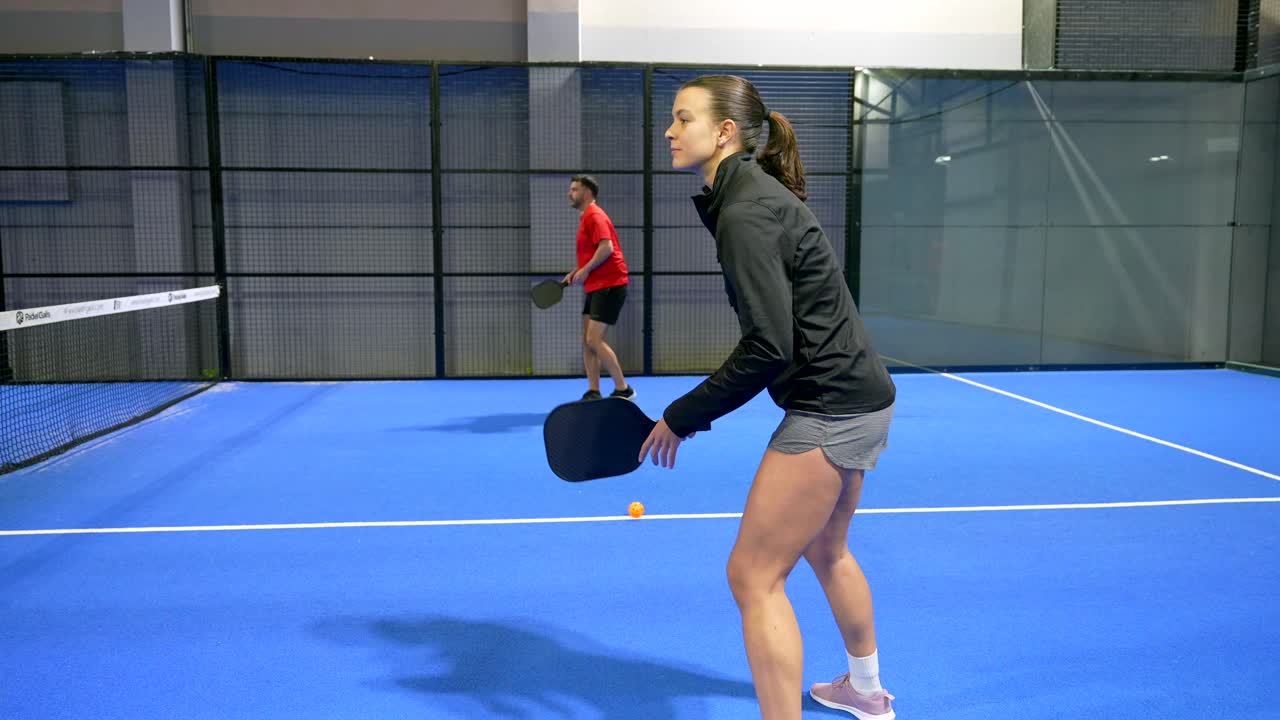 Woman and Man Playing Padel Tennis on an Indoor Court