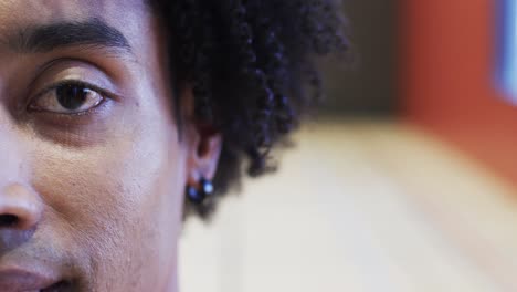 Half portrait of male african american basketball player in indoor court, in slow motion