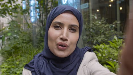 pov shot of muslim businesswoman making video call on mobile phone outdoors in city