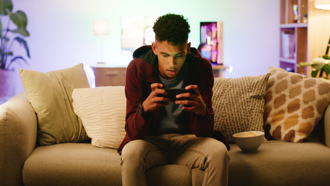 Un gamer maschio sicuro di sé che gioca a un videogioco mobile.