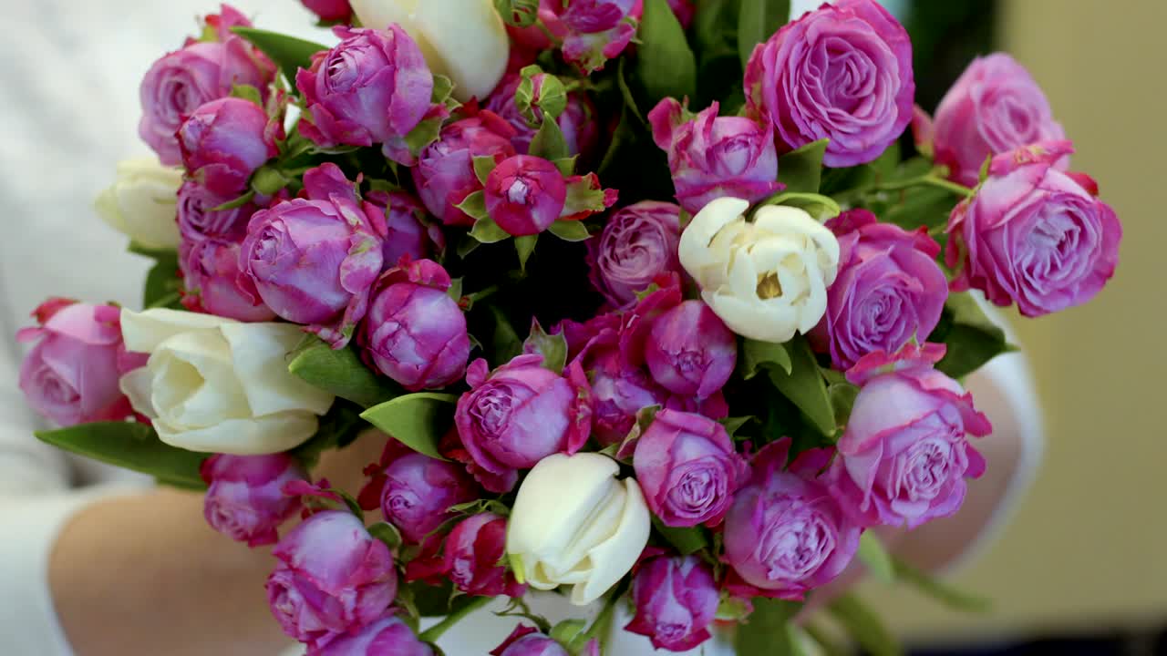 Mulher segura um buquê de tulipas e rosas.