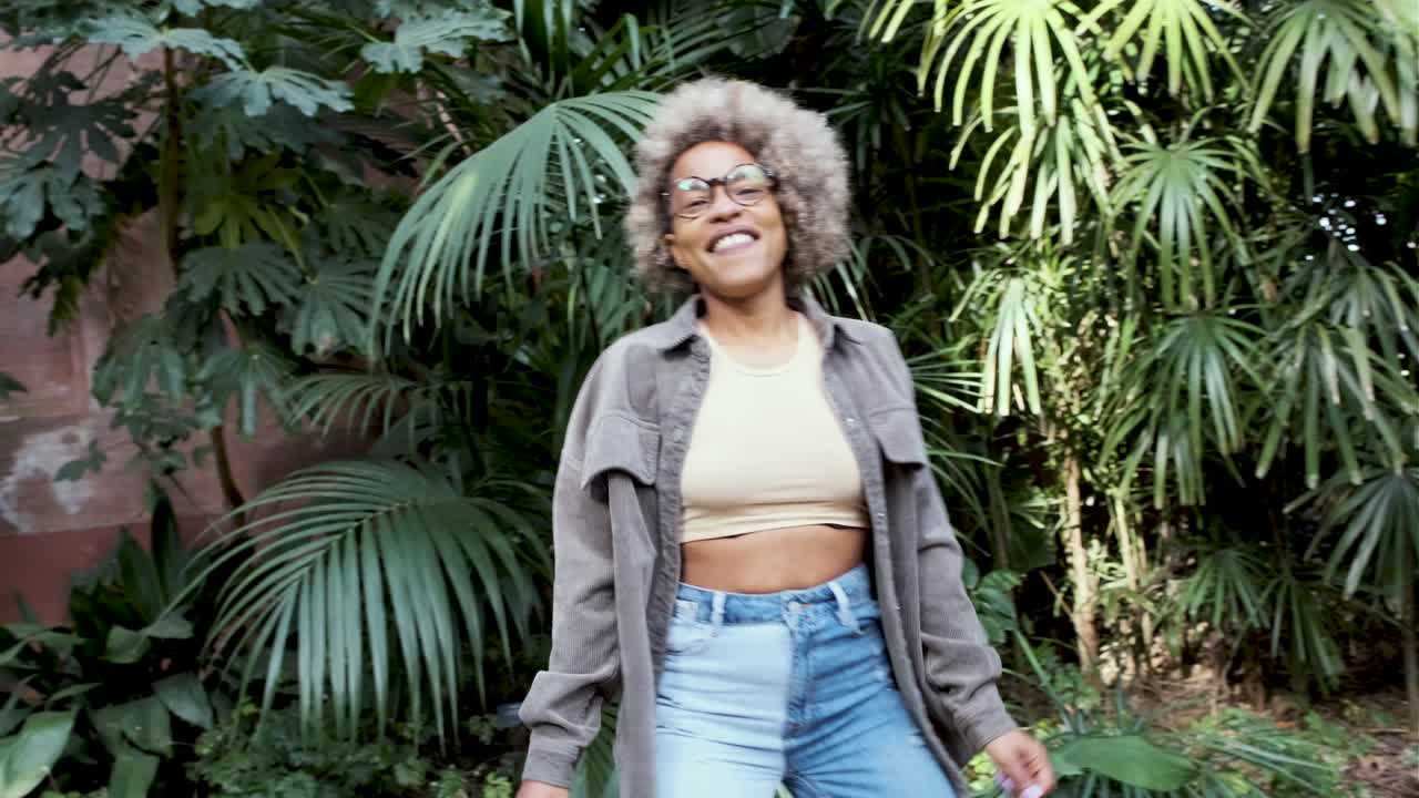 Fashionable woman in stylish outfit surrounded by lush greenery