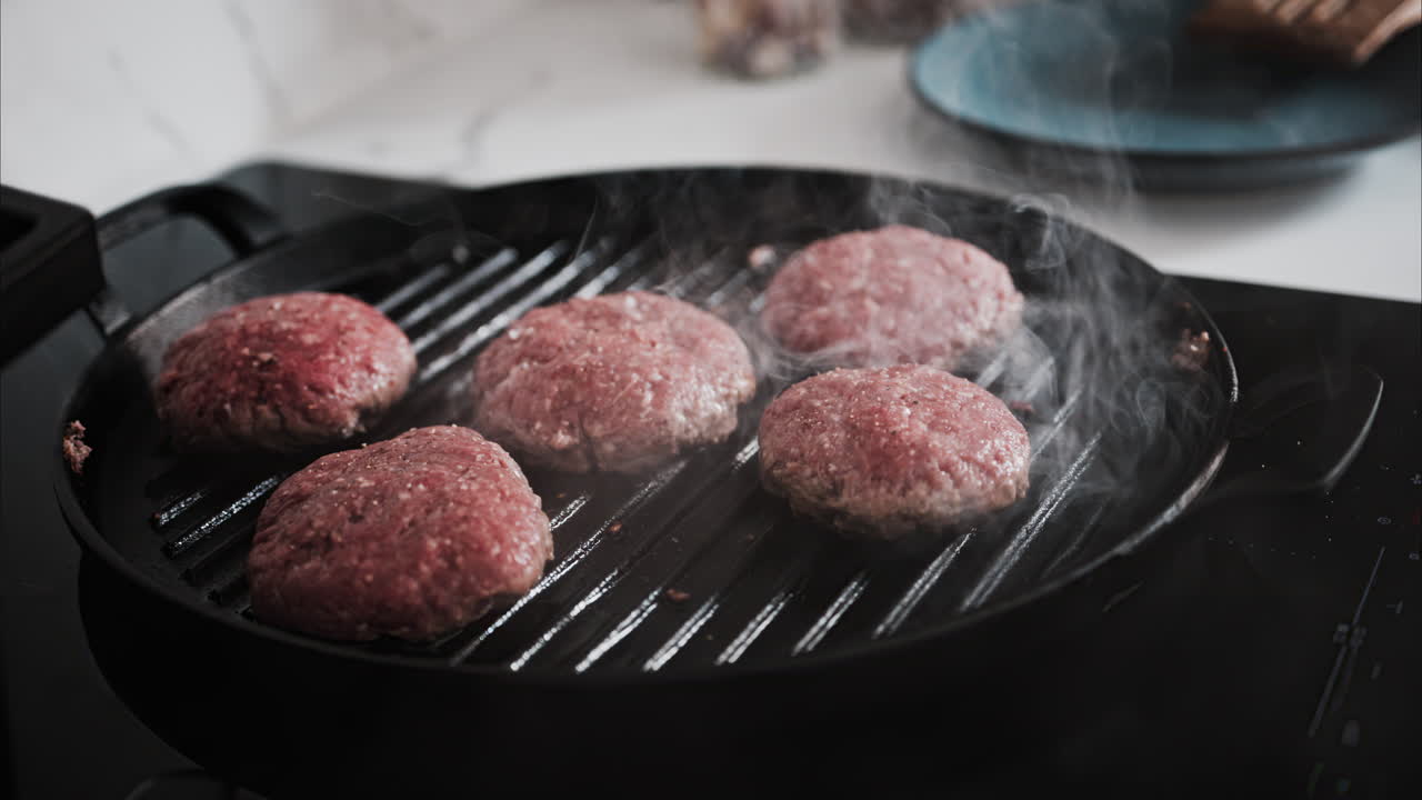 Burger patties being cooked on a grill pan