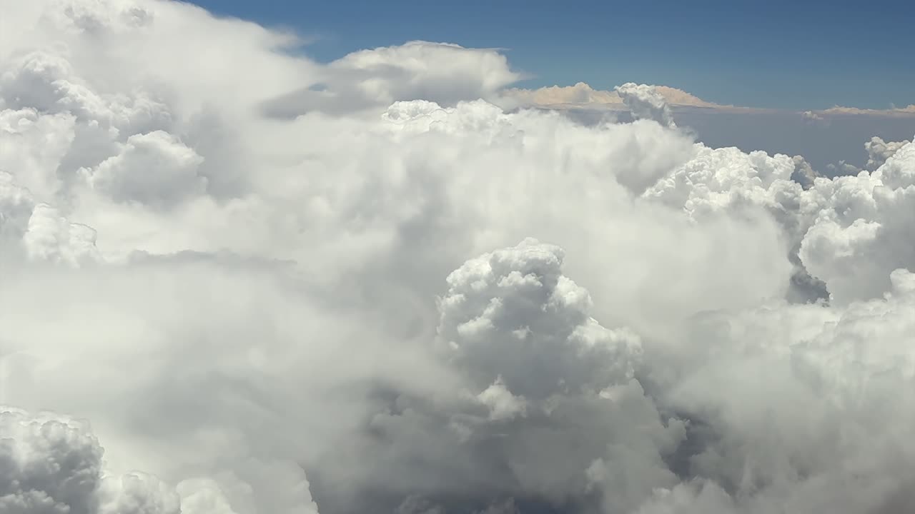 An immersive pilot’s POV view of theatening massive cumulonimbus storm clouds from a jet cockpit, while flying at very high altitude cruise level