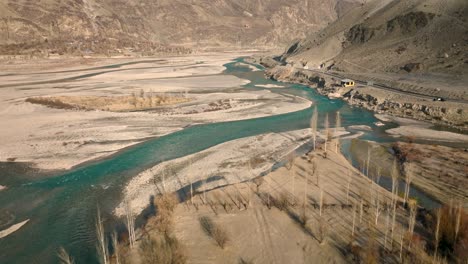 drone flying over turquoise winding river rising to reveal sweeping valley landscape of ghizer valley of gilgit baltistan