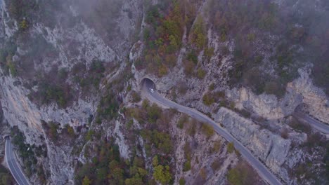 Coche-En-Coche-A-Través-Del-Túnel-En-El-Parque-Nacional-Durmitor-Con-Nubes-Bajas-Durante-El-Amanecer,-Otoño