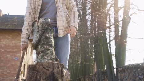 Close-up-view-of-unrecognizable-man-chopping-firewood-with-an-ax-outside-a-country-house