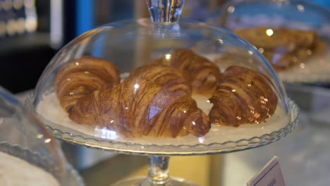 close-up of fresh croissants under a glass dome