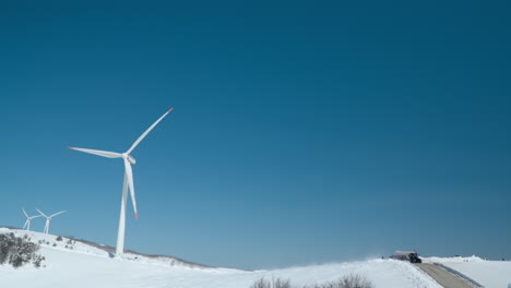 daegwallyeong sky ranch - massive wind turbines rotate blades against blue sky as tractor with trailer bring people to mountain summit, south korea travel