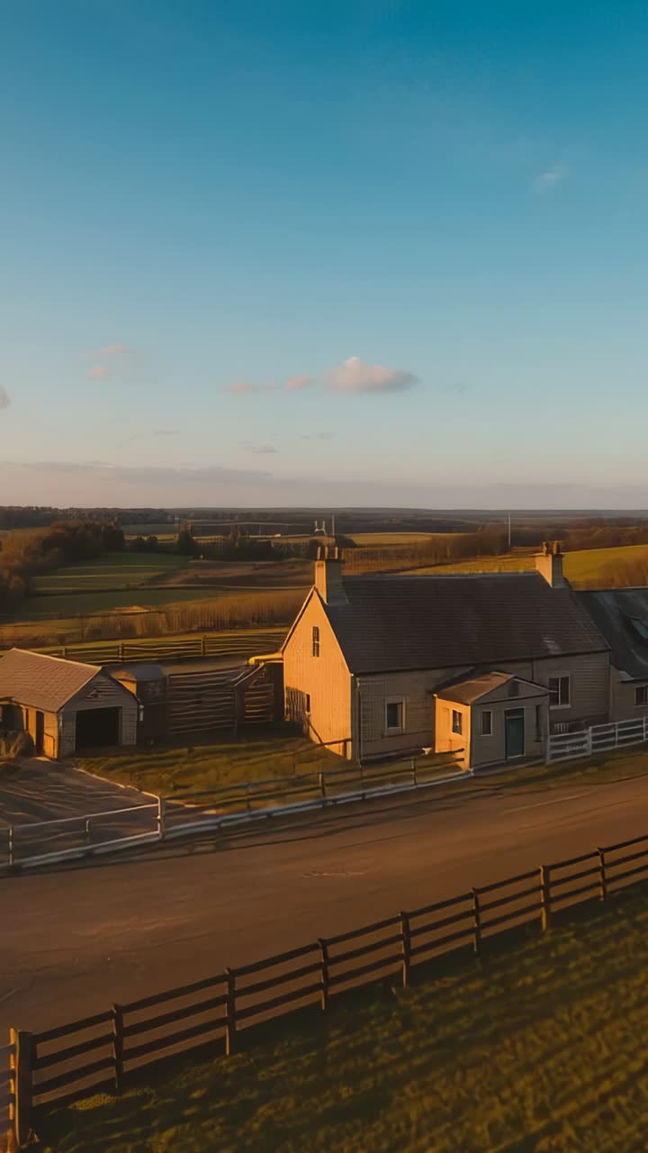 Vertical video: Hovering drone panning over farmhouse, barn and outbuilding by road showing fields