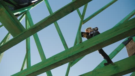 female builder working with a tablet among the rafters of an unfinished roof