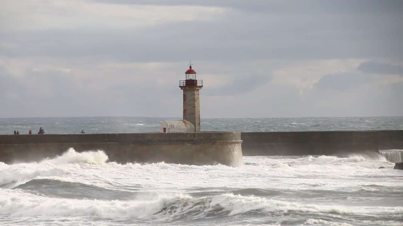 las olas aplastan el faro de oporto en una noche nublada y ventosa