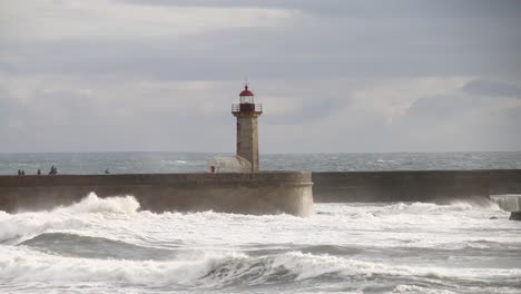 waves crushing lighthouse in porto in a cloudy and windy evening