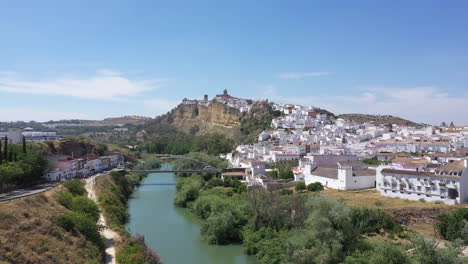 AERIAL---Guadalete-River,-Arcos-de-la-Frontera,-Cadiz,-Spain,-wide-shot-lowering