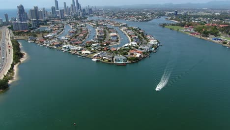 Barco-Individual-En-Un-Gran-Canal-Con-El-Horizonte-De-Surfers-Paradise-En-El-Fondo,-Hermoso-Día-Claro