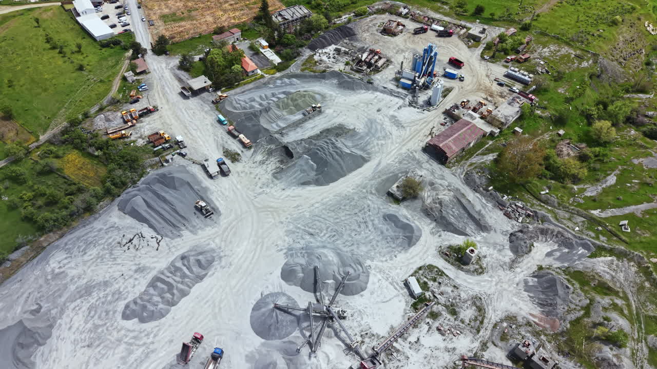 Construction site showing machinery and vehicles working on a gravel extraction area near a rural region in daylight