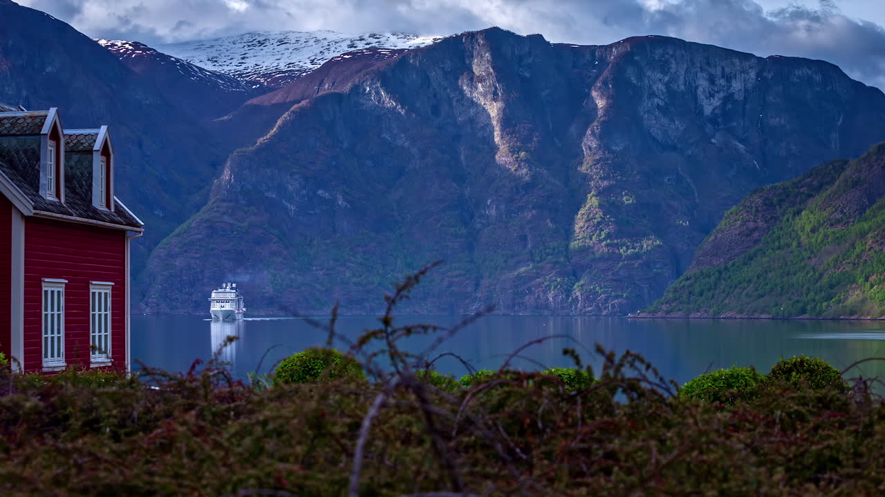 time-lapse de un crucero que entra en el lago flam fjord en noruega en medio de las montañas nevadas en un día nublado