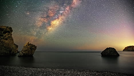 milky way time lapse over aphrodite's rock and a pebble beach in cyprus