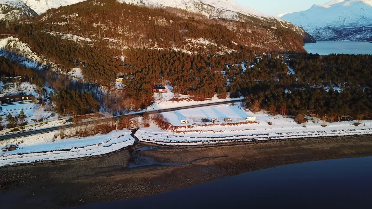 Drönarfilm över arktiska havsvågor mot strand där campare och vanlife-entusiaster har sina husbilar.