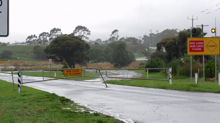 Flood water road closure sign, barrier and flashing lights for a flooded road