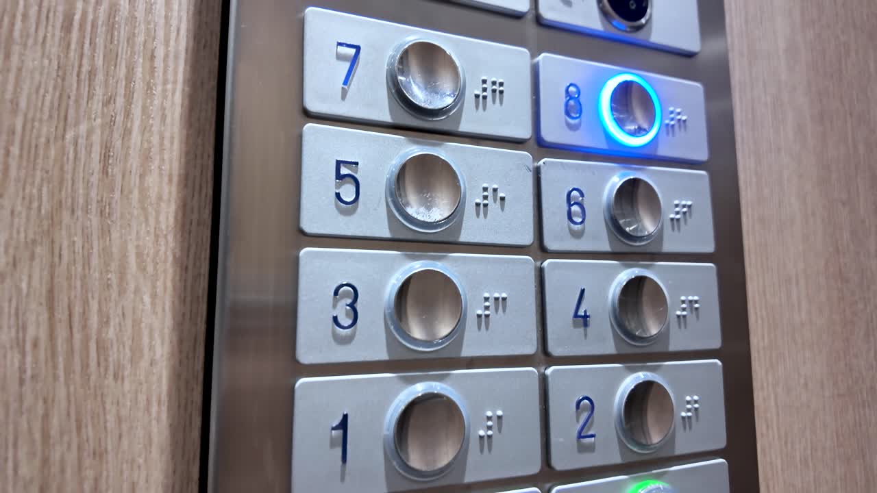Primo piano dei pulsanti argentati dell'ascensore con numeri e lettere in Braille in una cabina ascensore moderna per accessibilità e trasporto verticale