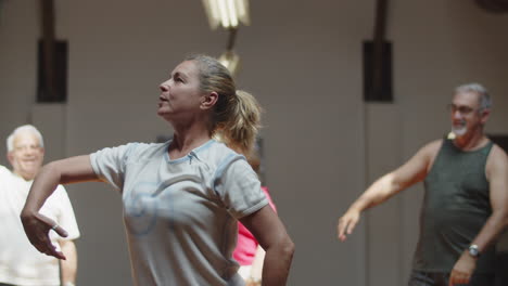 Cheerful-dance-teacher-dancing-with-senior-people-in-ballroom