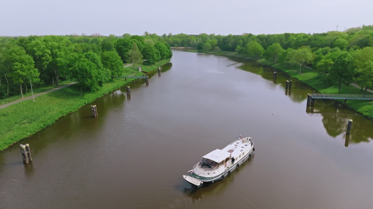 Tilt down showing a white boat moving through calm brown water under light clouds and soft daylight.