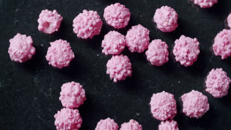 wide shot of pink particles moving on a black surface