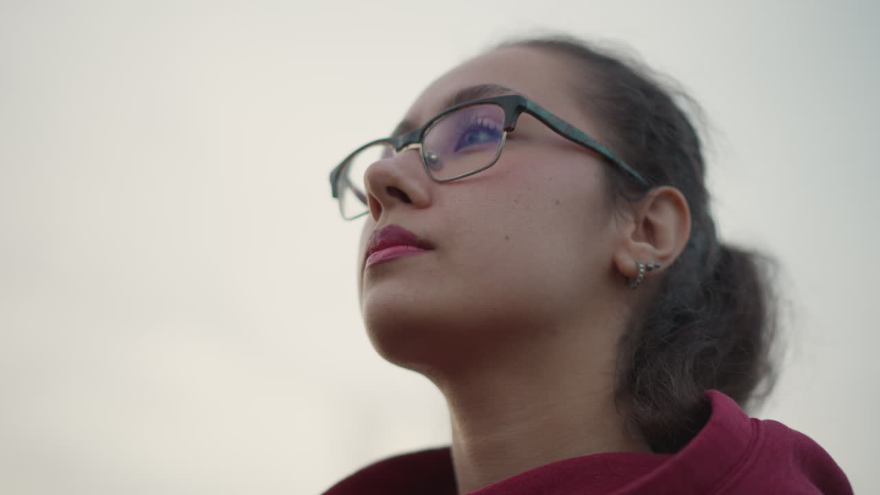 Girl Changing Hood As Woman Reflects Inwardly, Woman With Reflective Glasses And Hood Adjusting Herself Thoughtfully, Female Figure Focusing On Her Hood While Contemplating Deeply In Profile View
