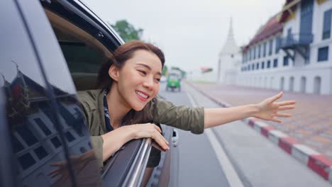 asian beautiful woman traveler open car window to face air outside. attractive young female tourist backpacker travel in beautiful city, spend time for road trip on holiday vacation trip in thailand.