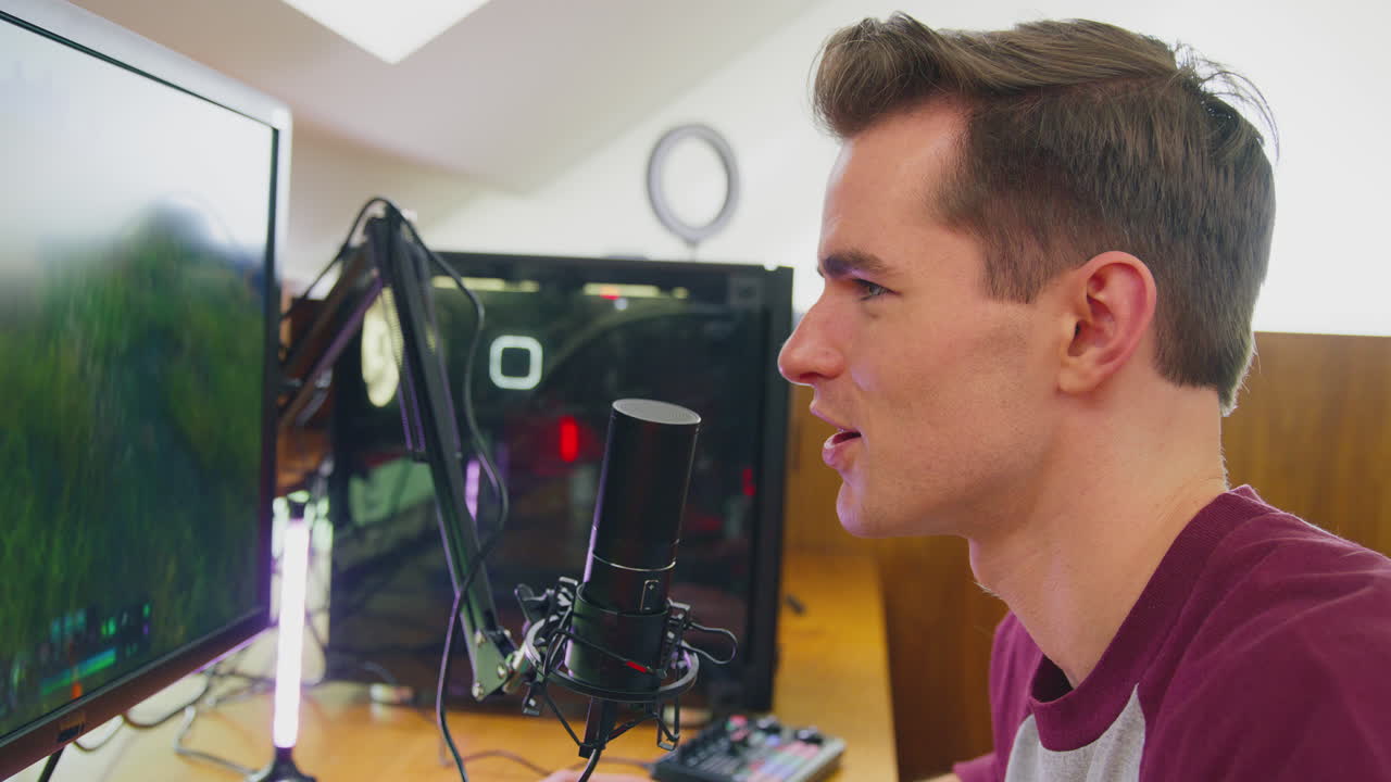 여러 모니터와 함께 책상에 앉아서 집에서 게임을 하는 남자