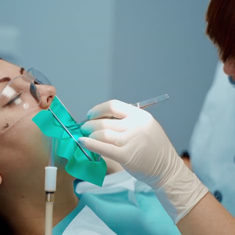 face of a patient in protective glasses in the dental chair. professional stomatologist treating woman's teeth in dental center. stomatology concept.