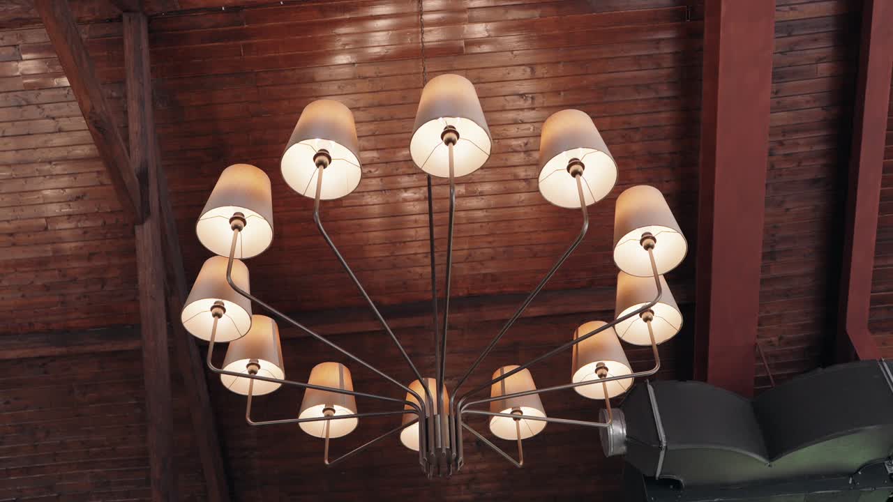 contemporary chandelier with curved arms and soft light hanging from wood ceiling