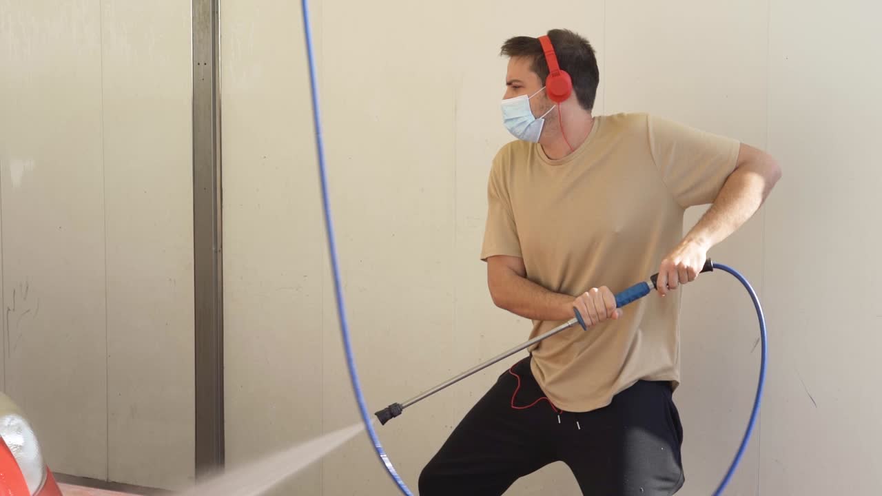Young Man Washing His Red Car with a Pressure Washer