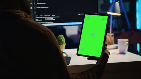 software developer programming in home office with green screen tablet