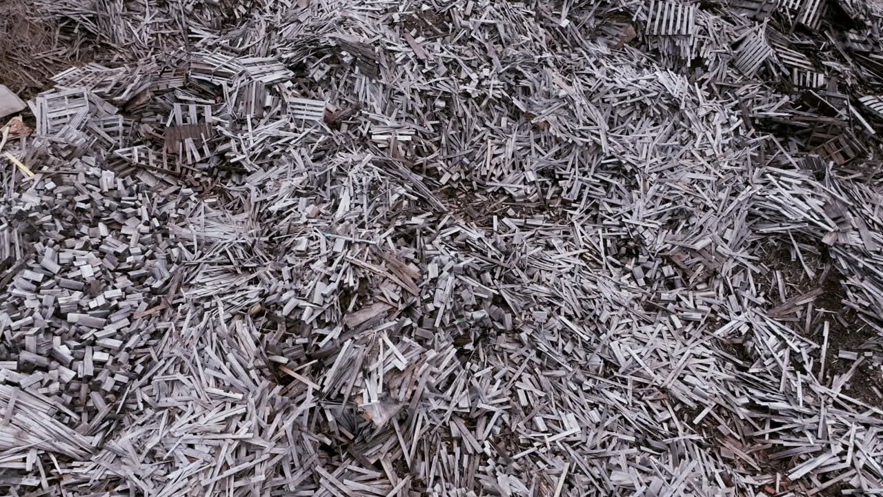 Aerial footage slowly flying over piles and piles of old wood at a factory.