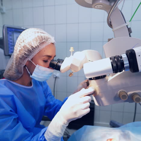 specialist looks through the microscope on patient's eyes in the operating room. female surgeon works with modern equipment in private clinic.