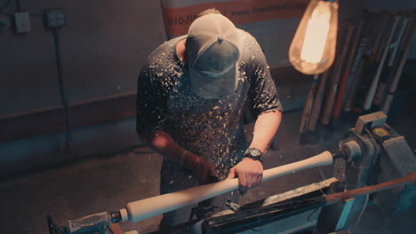 a man is carving a baseball bat in a shop