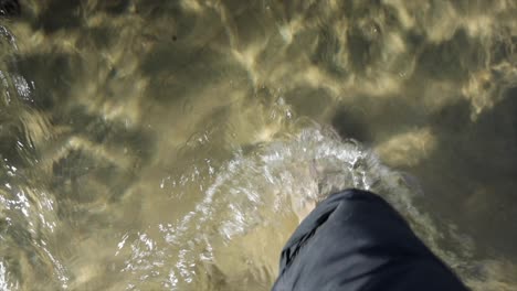 Close-up-of-feet-walking-in-clear-sea-with-sand---Scotland