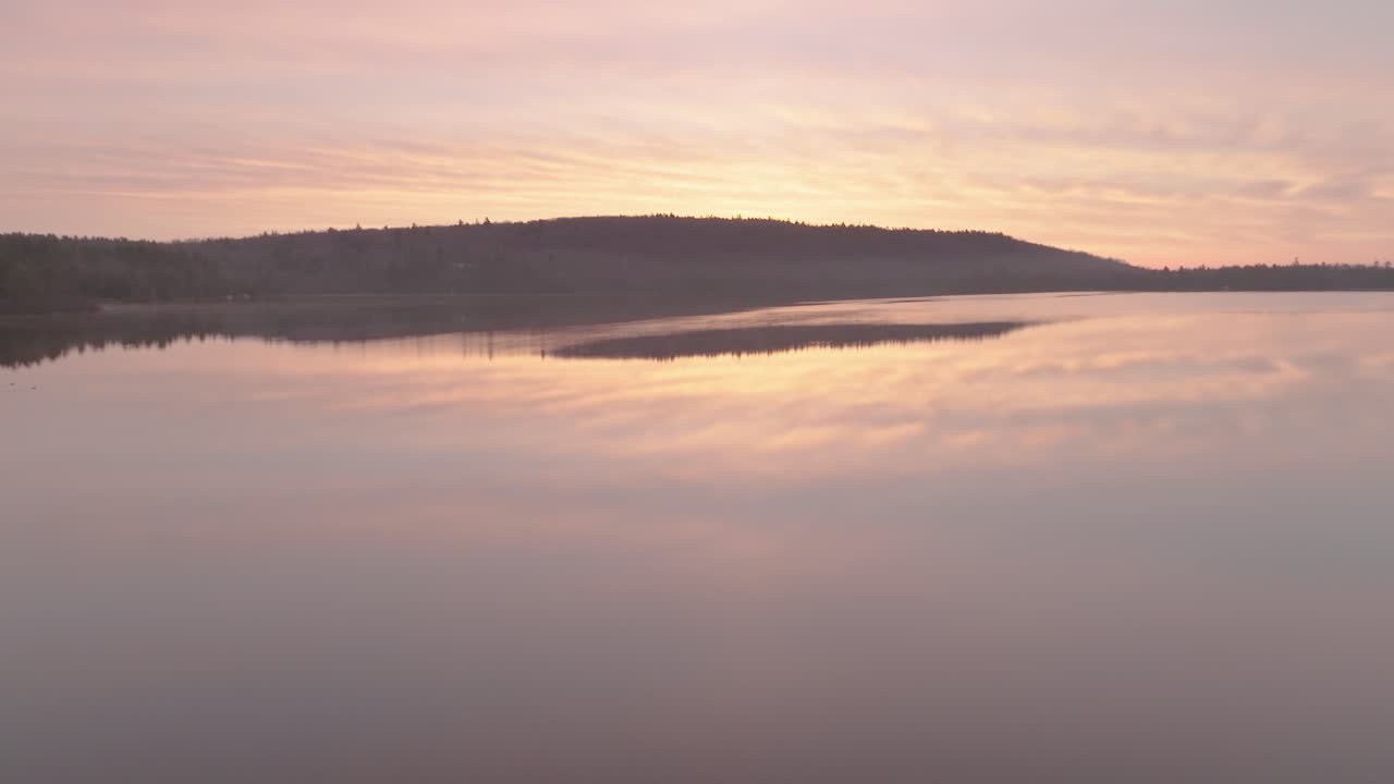평평한 아침에 몬슨 연못 위의 해가 뜨는 것
