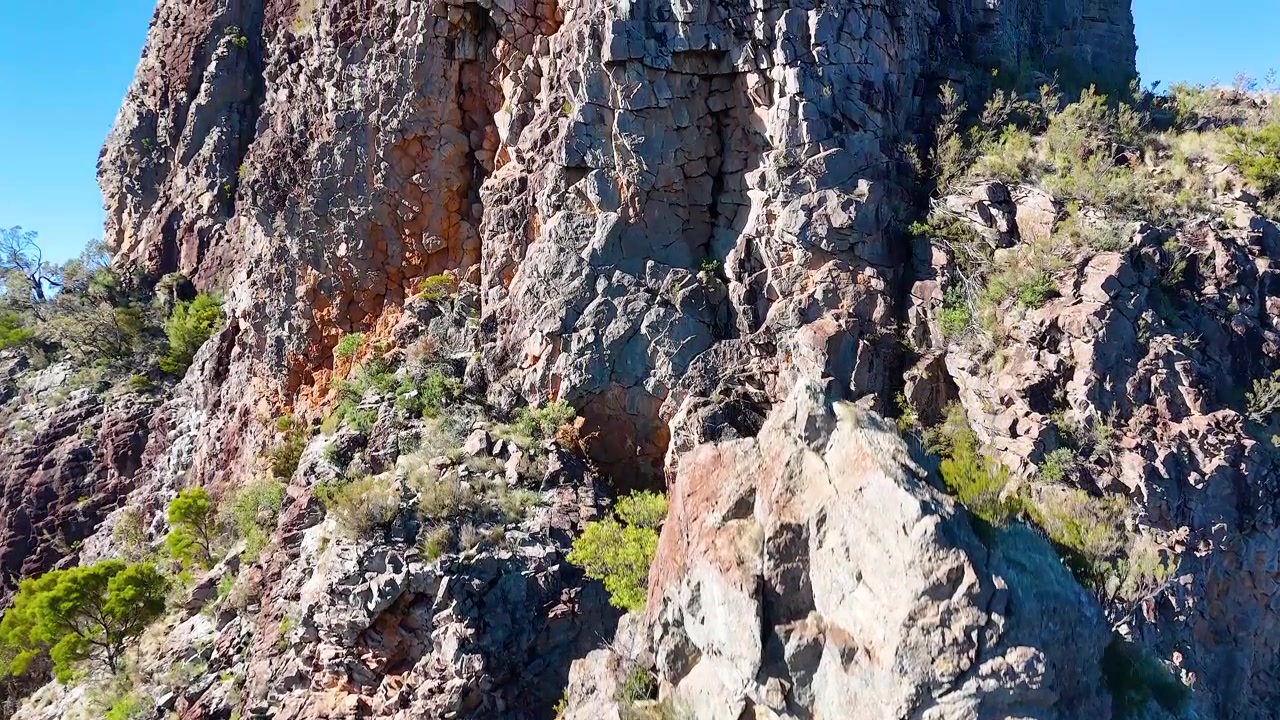Ripresa con drone in discesa oltre ripide scogliere di roccia vulcanica nel Parco Nazionale Warrumbungle, Australia.