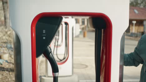 Man-with-sunglasses-takes-the-charging-cable-from-the-charging-station