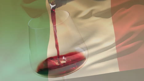 compuesto de vino tinto que se vierte en un vaso sobre la bandera de italia de fondo