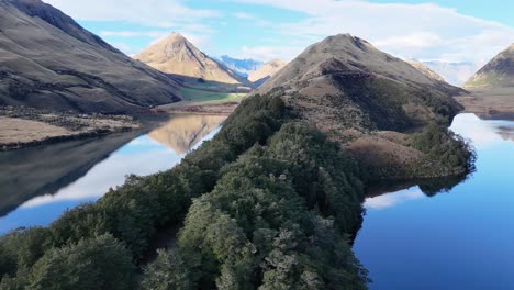aerial footage captures lake moke's serene landscape with lush greenery and reflective waters under clear skies in queenstown, new zealand