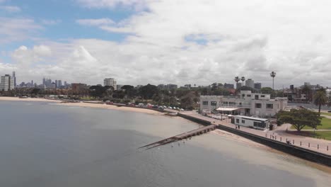 Aerial-panning-shot-showing-coastline-of-Melbourne-with-sandy-beach,-skyline-and-ocean-water-during-sunny-day