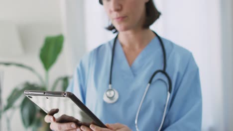 caucasian female doctor at home using tablet