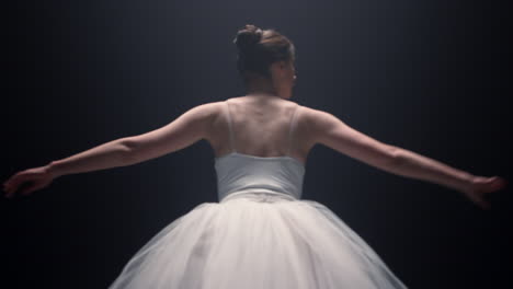 pretty ballet dancer spinning around indoors. ballerina dancing in dark space.