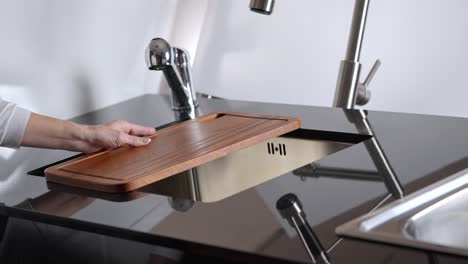 encimera de cocina con corte de madera y grifo de metal en cocina de acero