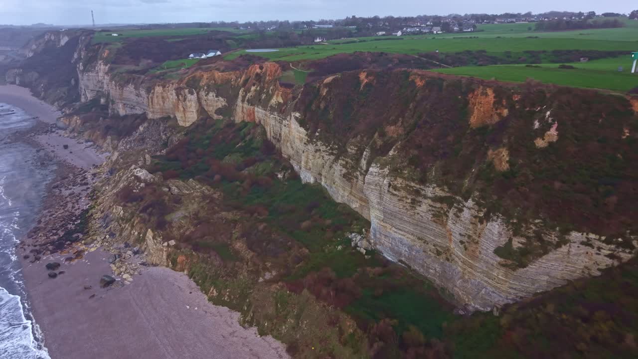 Drone che si allontana da scogliere e spiaggia, rivelando il paesaggio costiero della Spiaggia di Saint Jouin Bruneval, Francia.